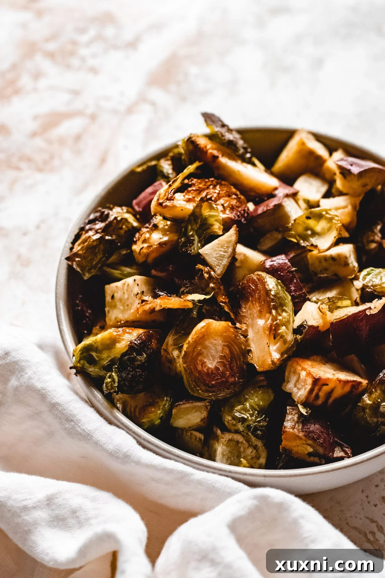 A close-up of a bowl filled with perfectly roasted Brussels sprouts and caramelized sweet potatoes, garnished with fresh herbs, ideal for a festive meal.