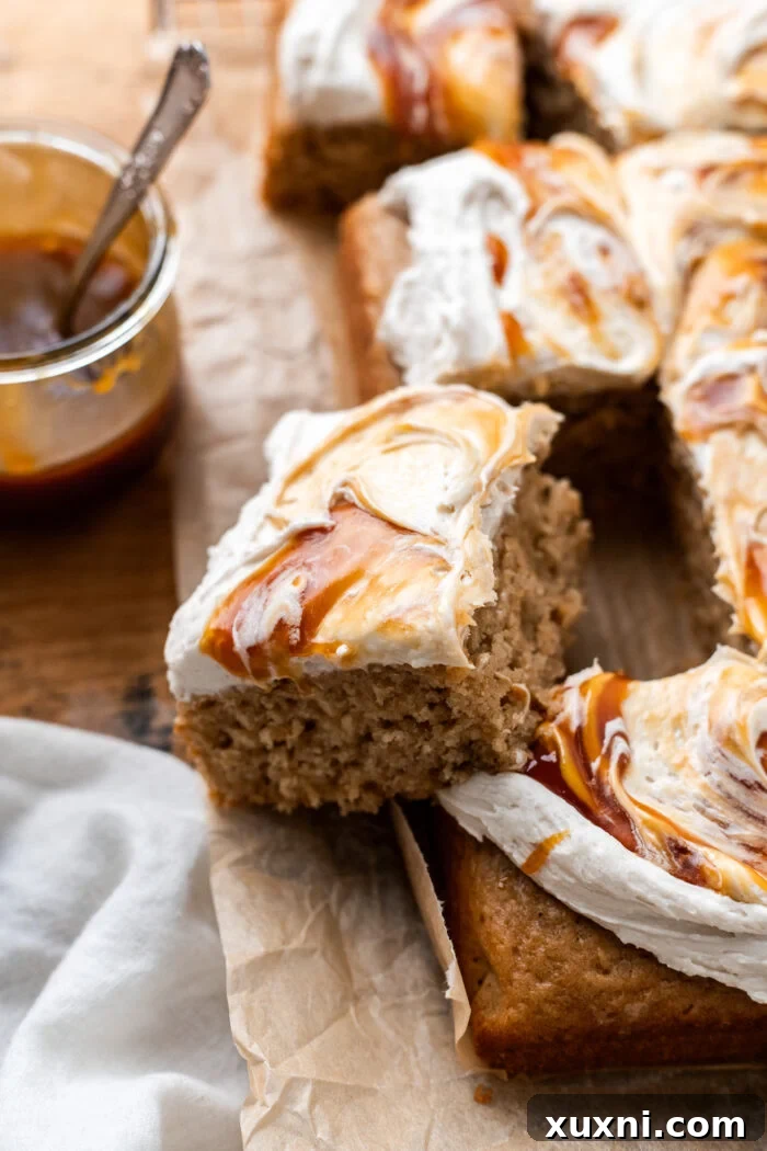 A close-up shot of a slice of vegan apple spice cake, revealing its delicate crumb and the rich layers of frosting and caramel.