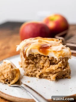 A delicious slice of vegan apple spice cake, with a bite taken out, showing its fluffy texture and rich frosting.
