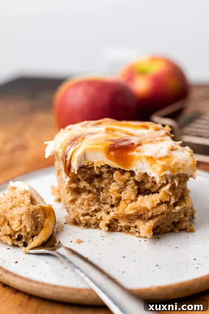 A delicious slice of vegan apple spice cake, with a bite taken out, showing its fluffy texture and rich frosting.