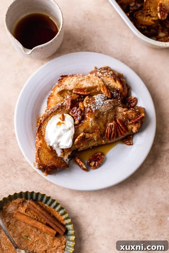 A slice of vegan French toast casserole on a plate, topped with fresh berries and maple syrup.
