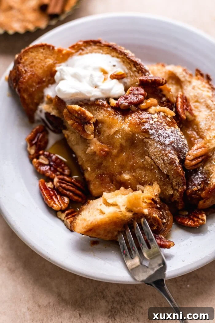 A serving of baked vegan French toast casserole on a plate, garnished with powdered sugar and berries.