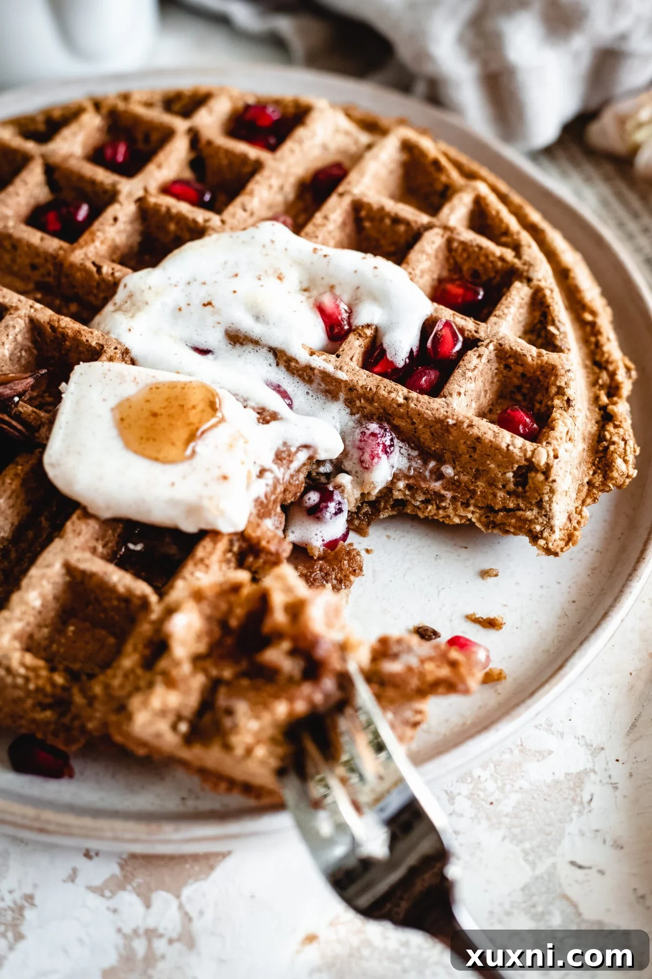 Effortless Gluten Free Vegan Pumpkin Waffles 4 A freshly cooked gluten-free vegan waffle, partially eaten, on a white plate