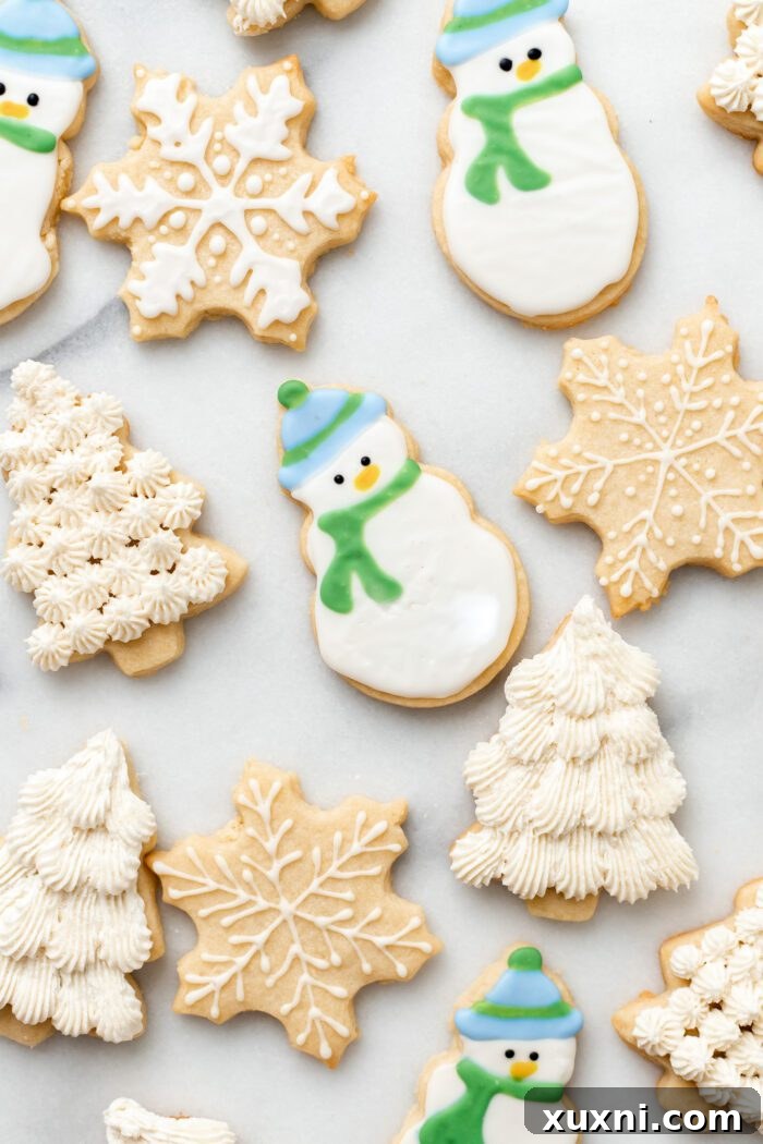 vegan sugar cookies decorated as snowmen, Christmas trees, and snowflakes on marble