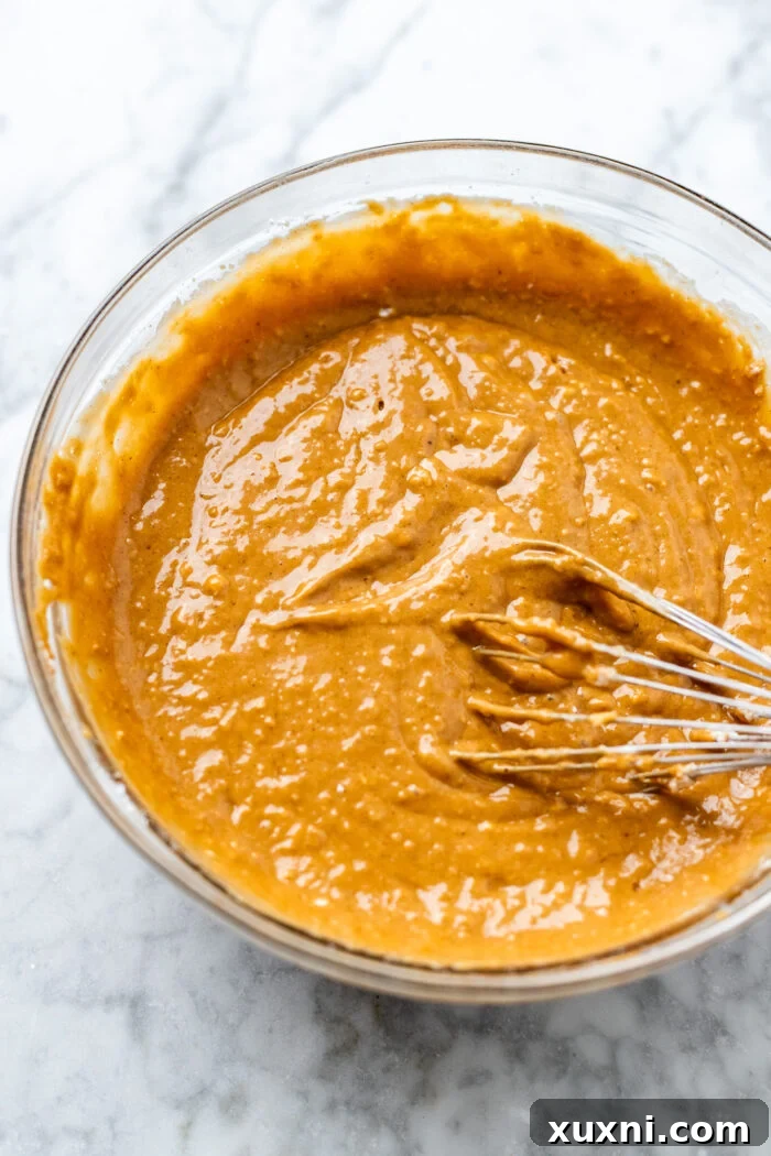 Close-up of a bowl filled with a smooth, spiced vegan gingerbread loaf batter, ready to be poured into the baking tin, showcasing its rich brown color.
