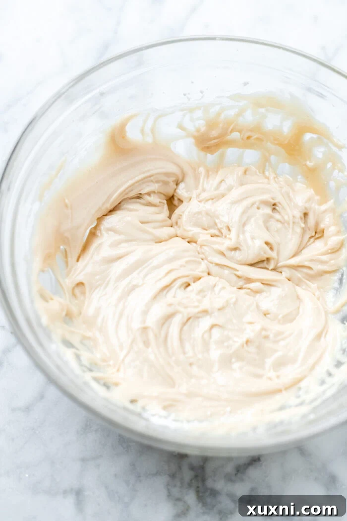 A bowl of creamy, fluffy vegan maple cashew cream frosting, perfectly whipped and ready to be spread onto the cooled gingerbread loaf cake, promising a delightful finish.