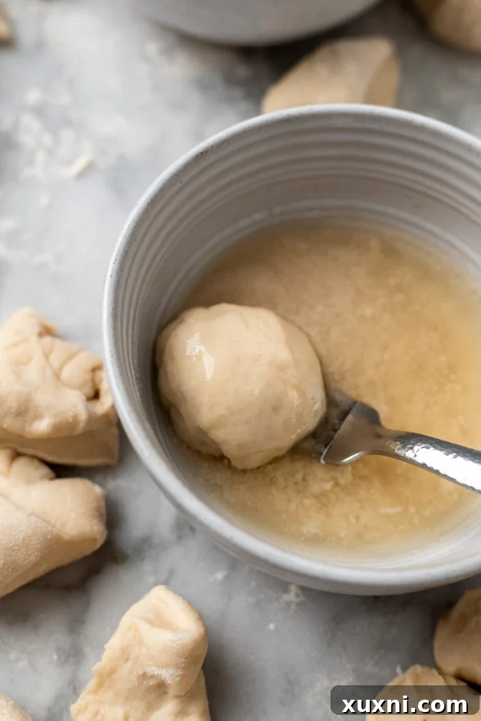 The Ultimate Easy Vegan Pull-Apart Bread 8 A dough ball being dipped into a bowl of melted vegan butter.