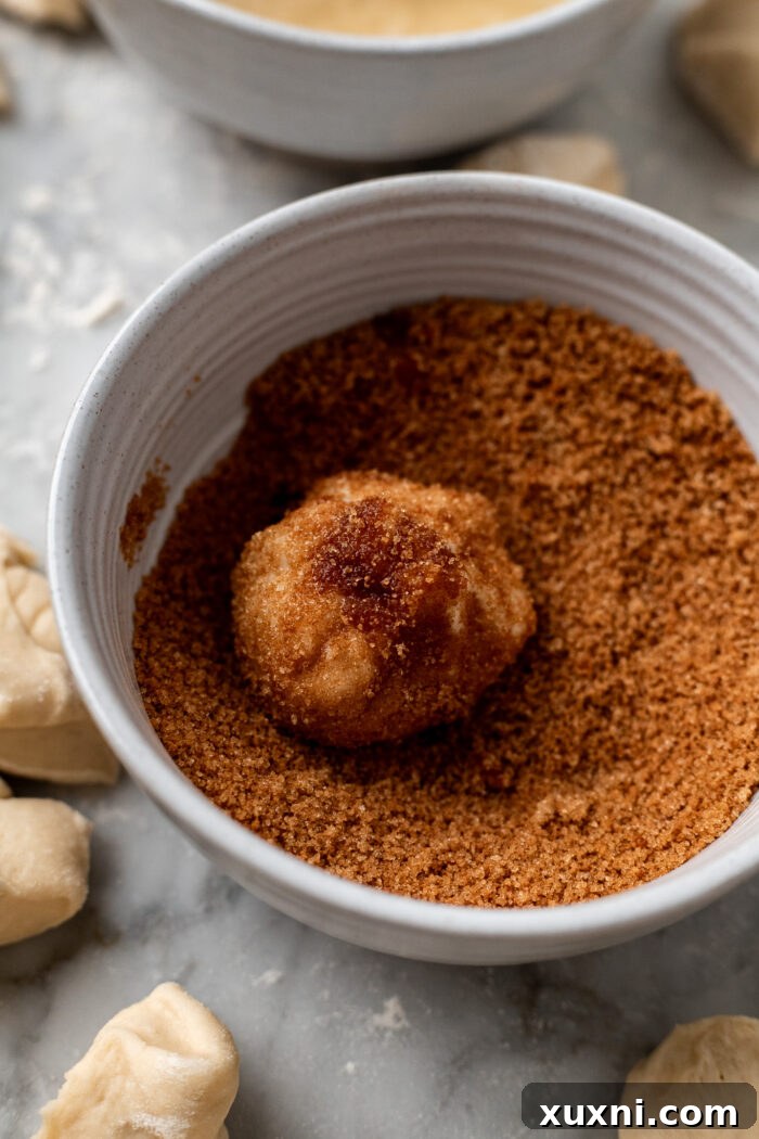 The Ultimate Easy Vegan Pull-Apart Bread 9 A butter-dipped dough ball being coated in a cinnamon sugar mixture.