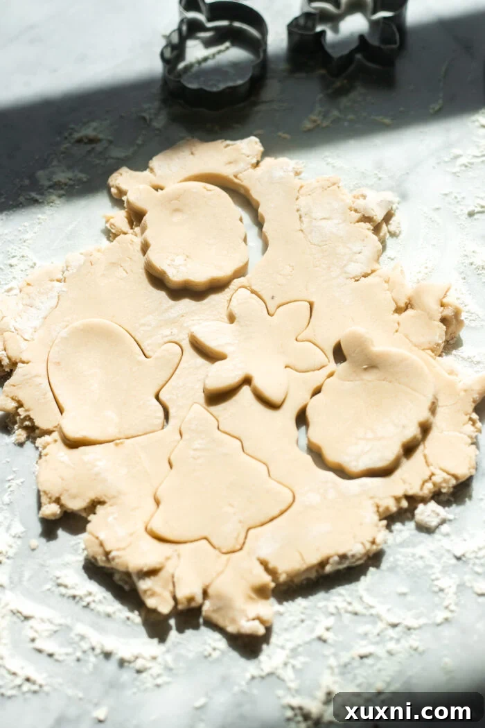 Cookie cutters pressing into vegan sugar cookie dough to create festive shapes.