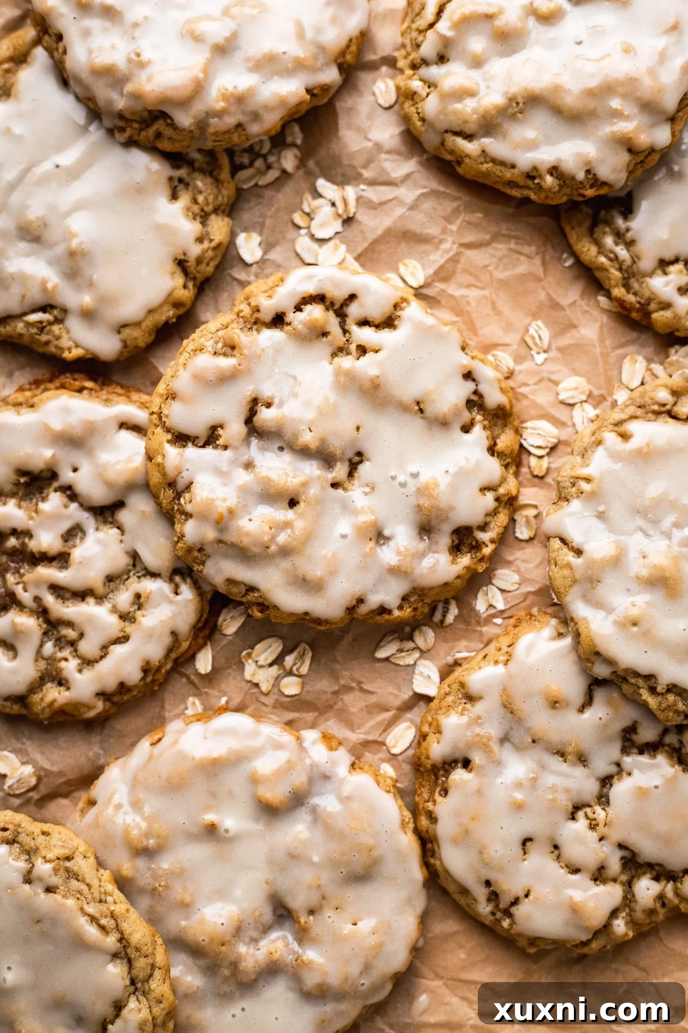 Iced vegan oatmeal cookies arranged on parchment paper, allowing the glaze to set