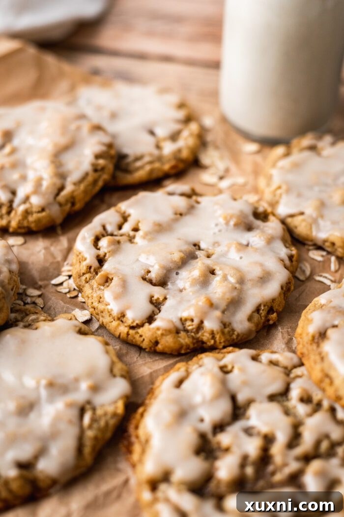 Iced vegan oatmeal cookies arranged on parchment paper, awaiting the glaze to set