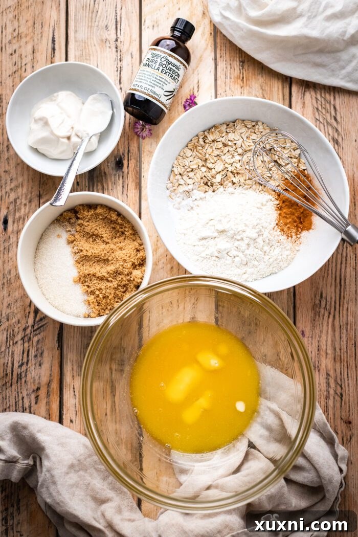 Assortment of ingredients for vegan oatmeal cookies laid out on a table, including oats, flour, and spices