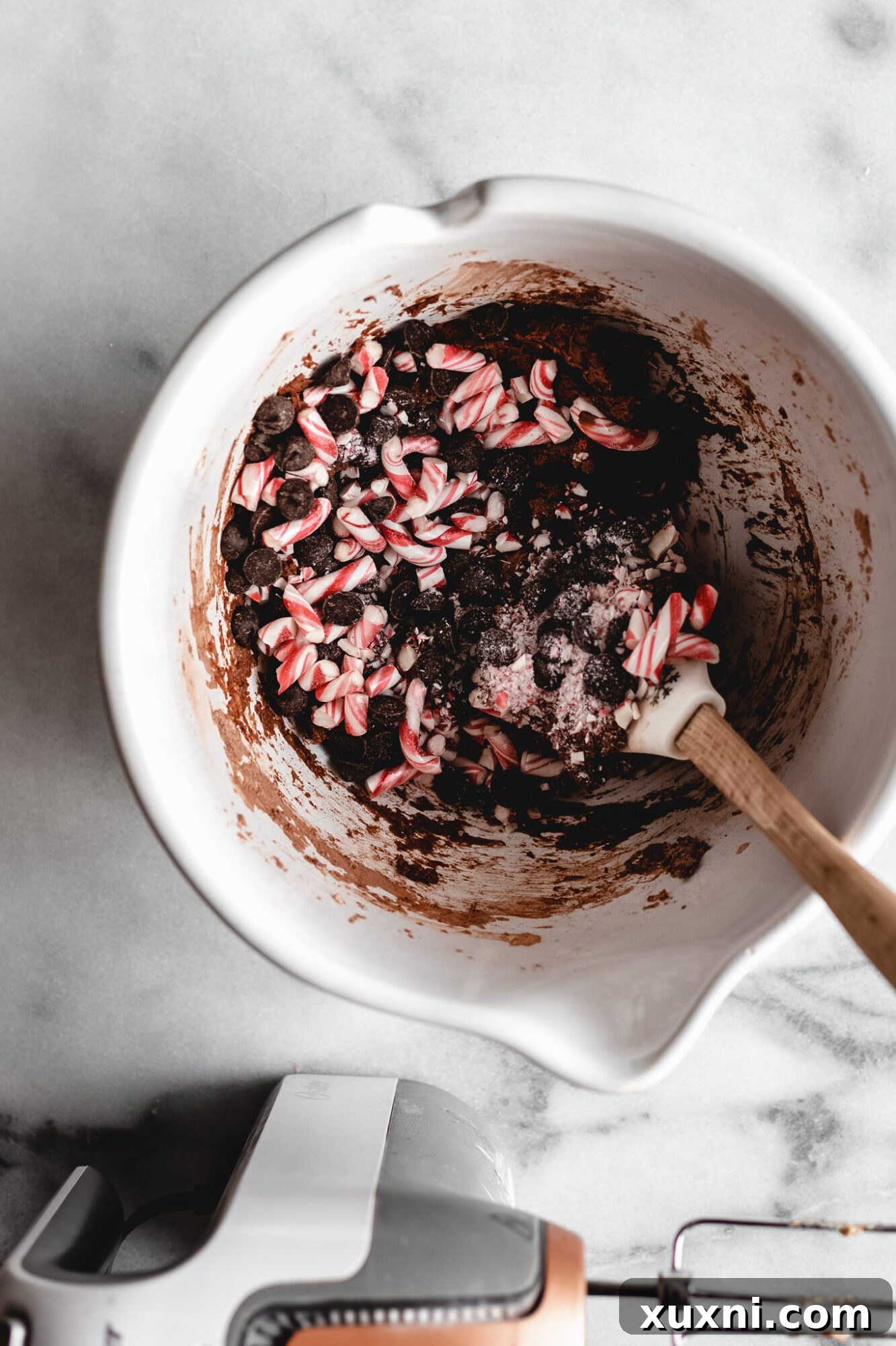 Peppermint candies being folded into chocolate cookie dough