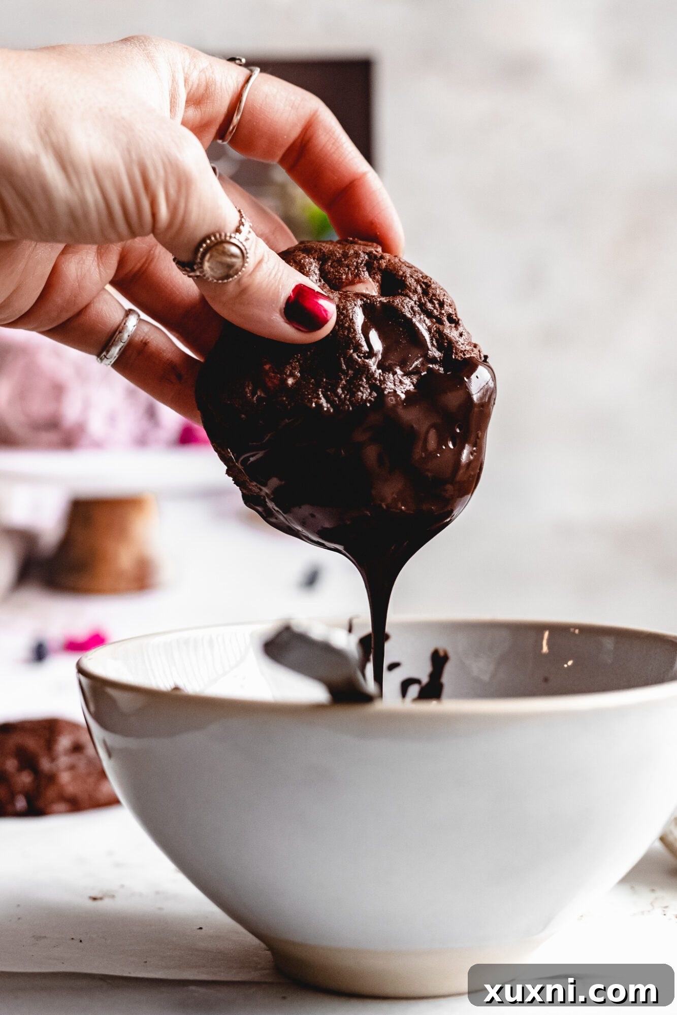 Hand dipping a vegan chocolate peppermint cookie into melted chocolate