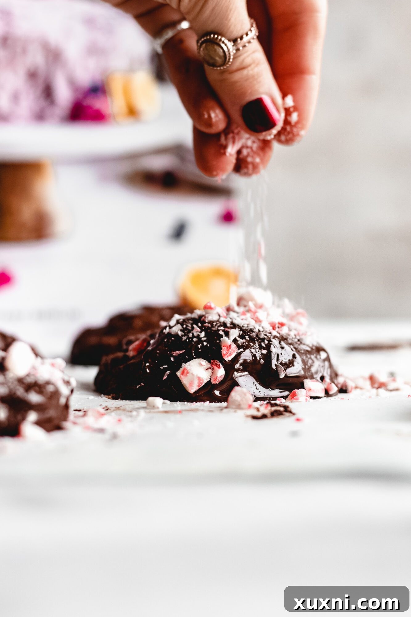 Two chocolate-dipped vegan peppermint cookies being prepared