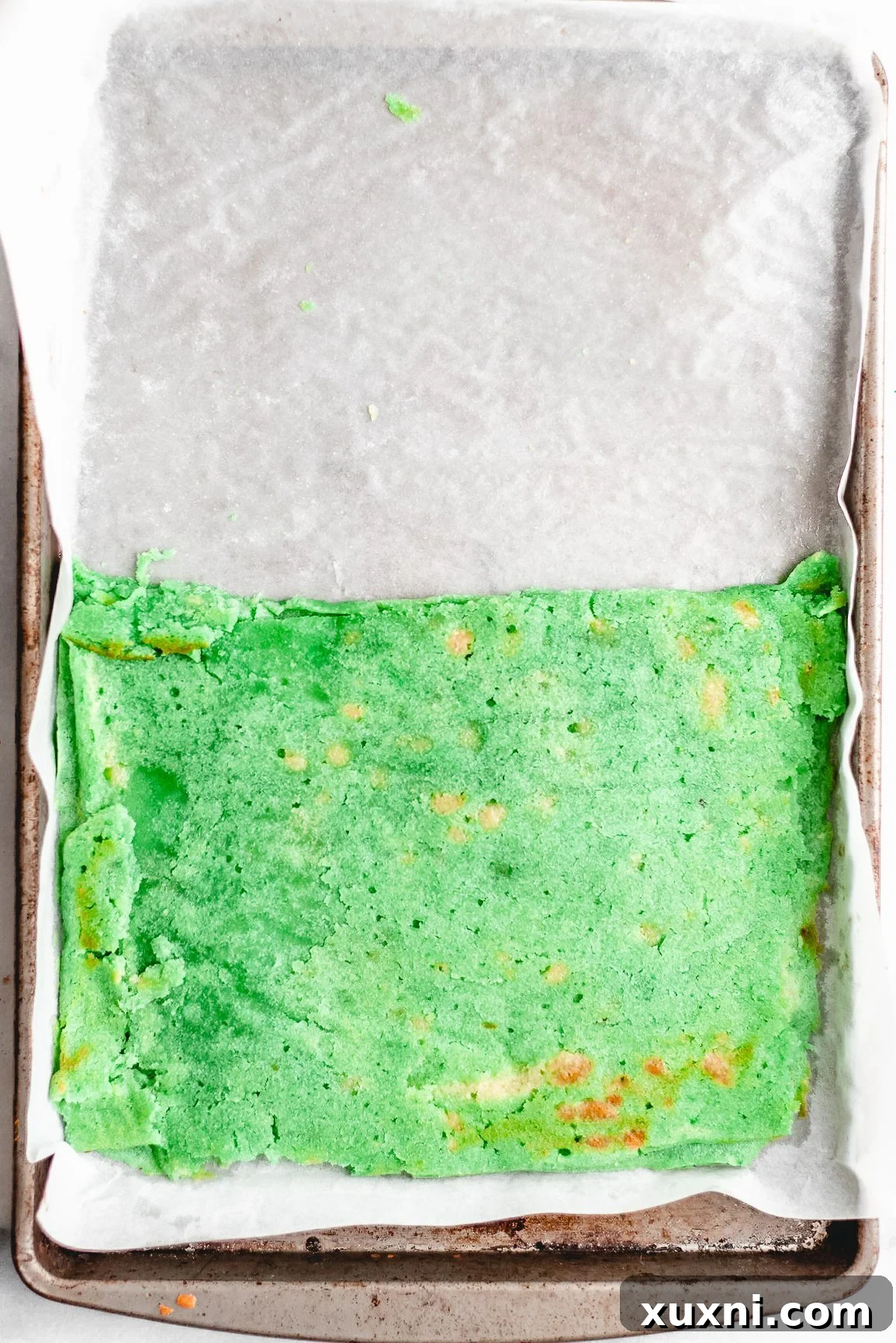 A baked rainbow cookie layer carefully folded in half.