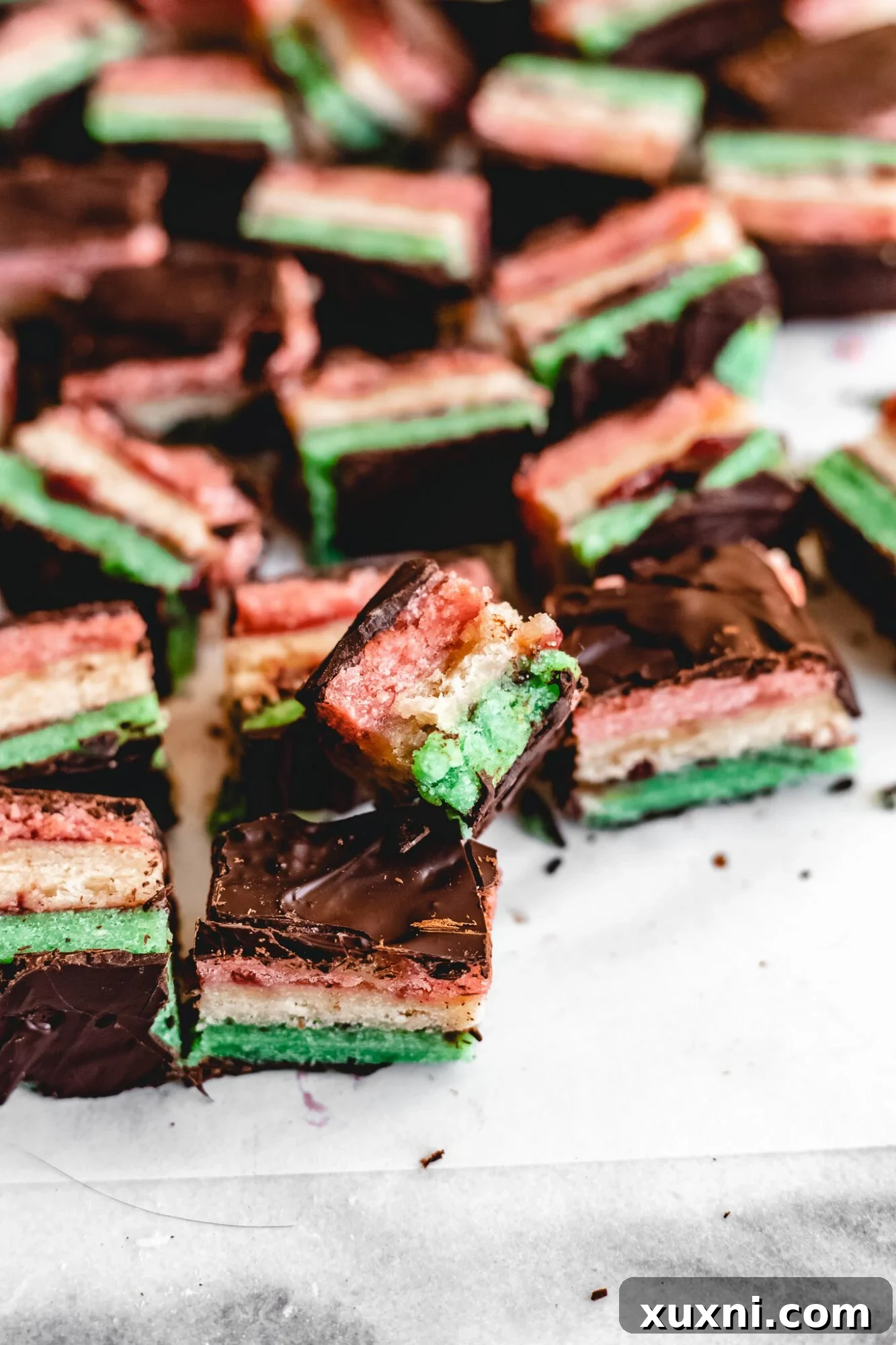 A bitten Italian tricolor cookie revealing the colorful almond cake and jam layers.