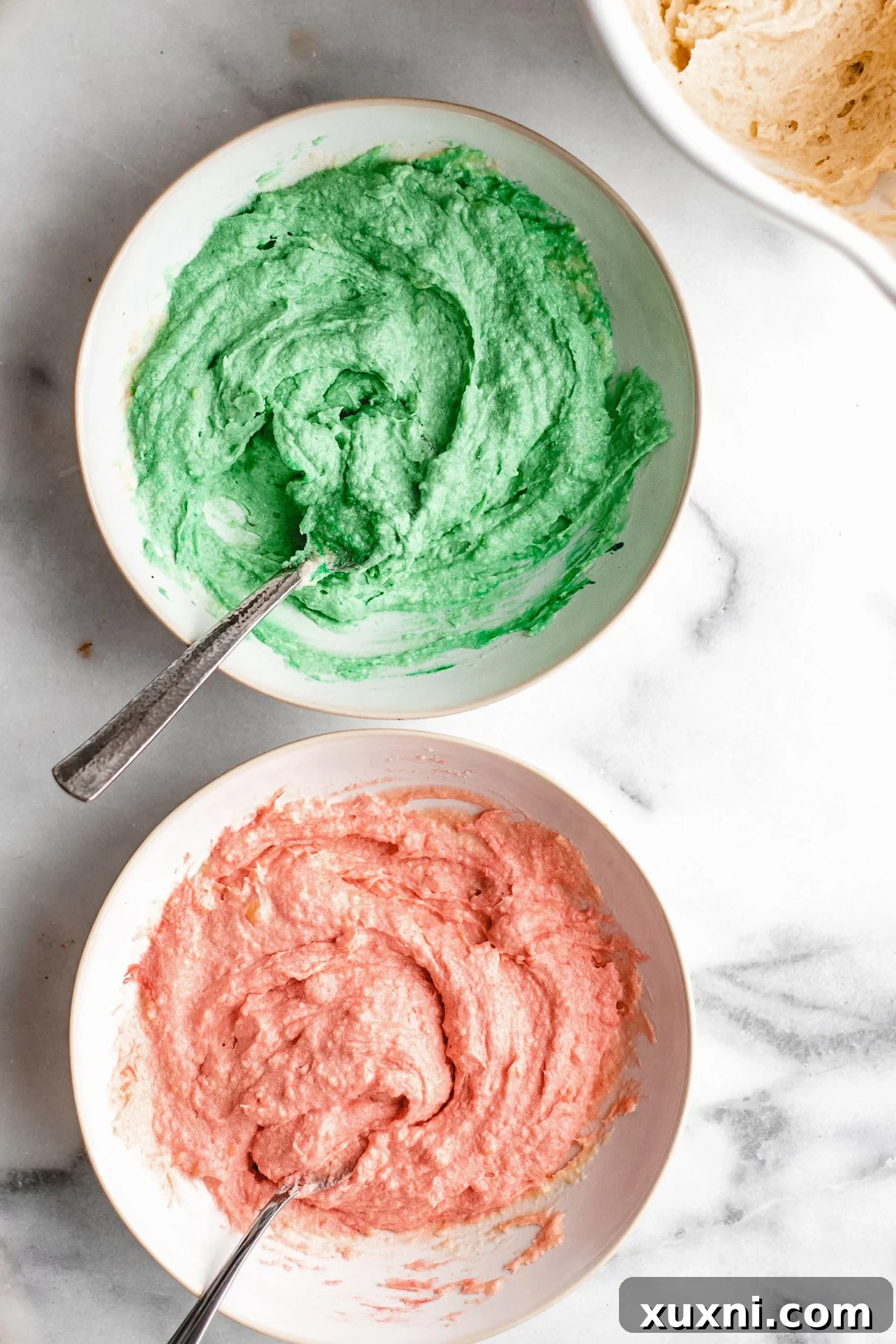 Three bowls of cookie dough batter, colored red, white, and green.