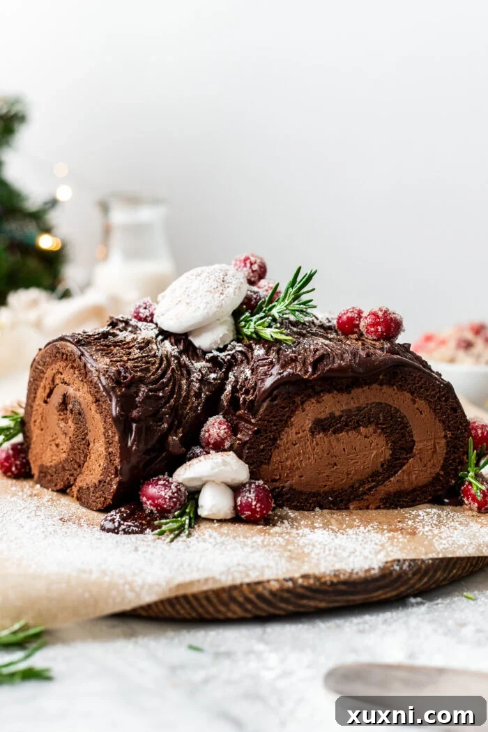 Vegan Christmas Yule Log Cake (Bûche De Noël) on a wood board, adorned with festive decorations.