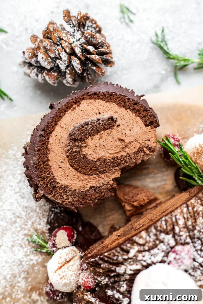 A perfectly sliced vegan Yule Log Cake revealing layers of chocolate sponge and hazelnut buttercream.