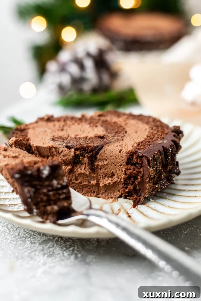 A tantalizing slice of vegan Yule Log Cake served on a white plate, ready to be enjoyed.