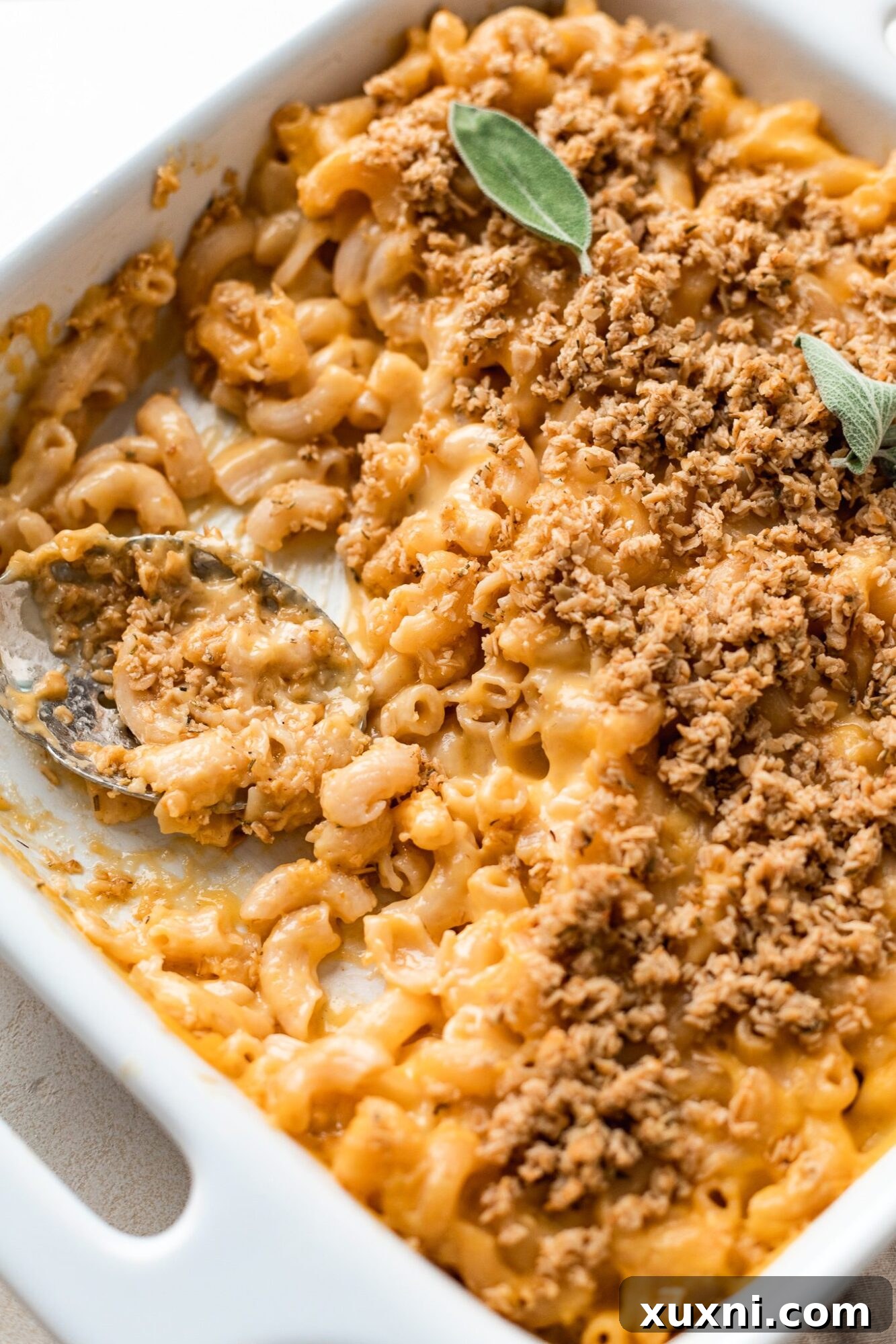A golden casserole dish of baked vegan mac and cheese, fresh from the oven, with a crispy topping.