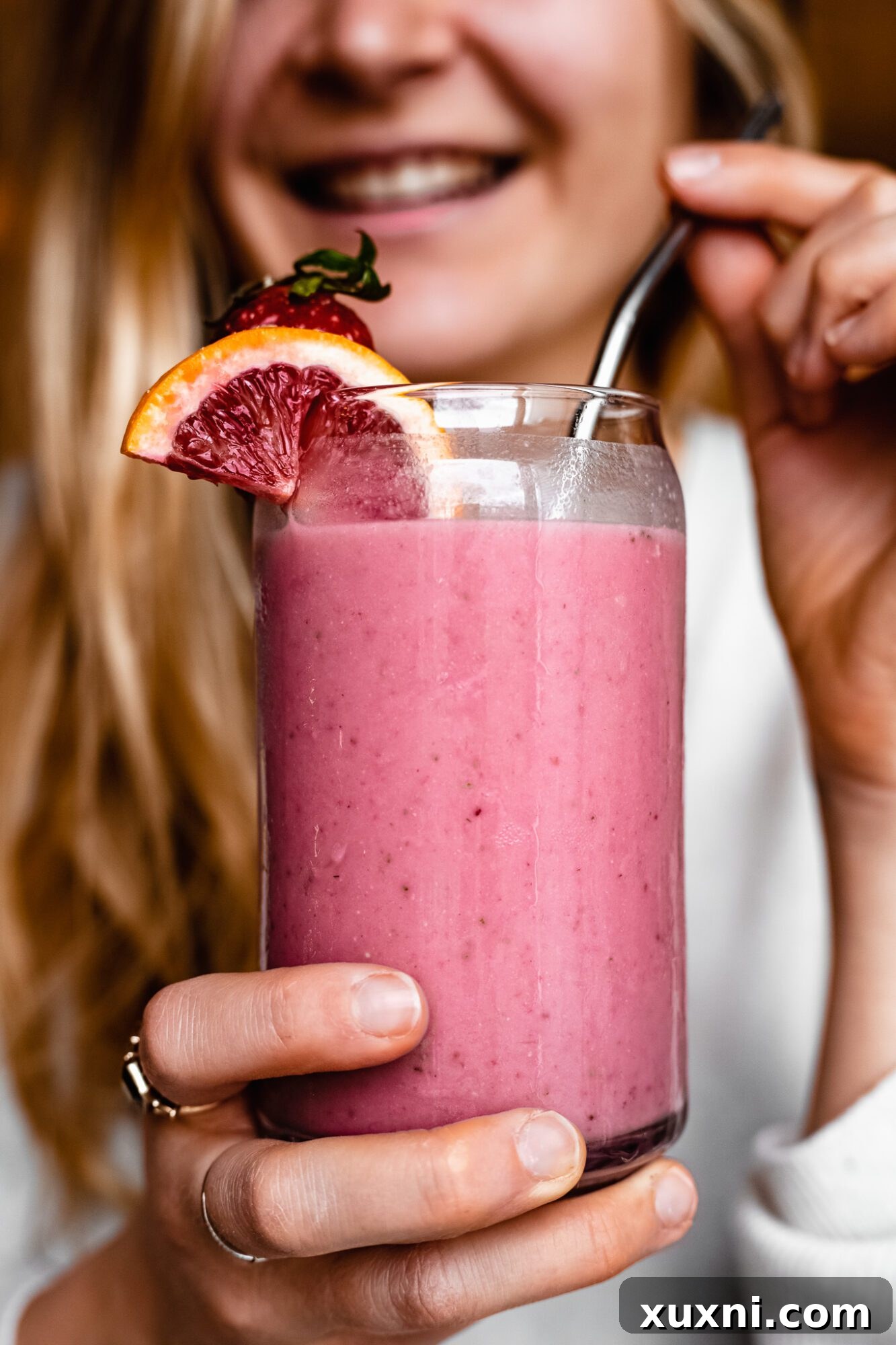 Hand holding a glass of Immune Boosting Strawberry Orange Smoothie