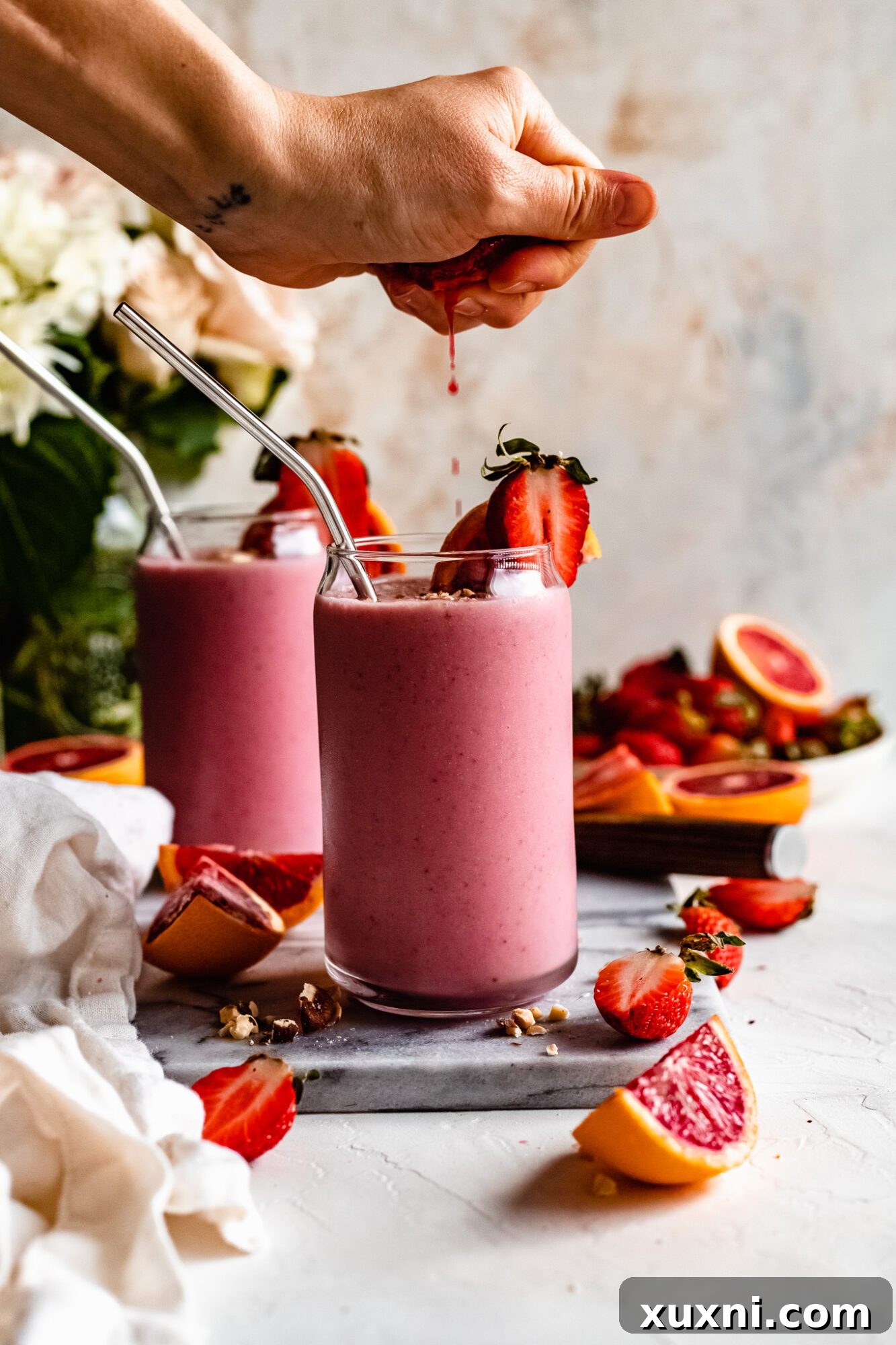 Hand squeezing fresh orange juice into a blender for a strawberry orange smoothie