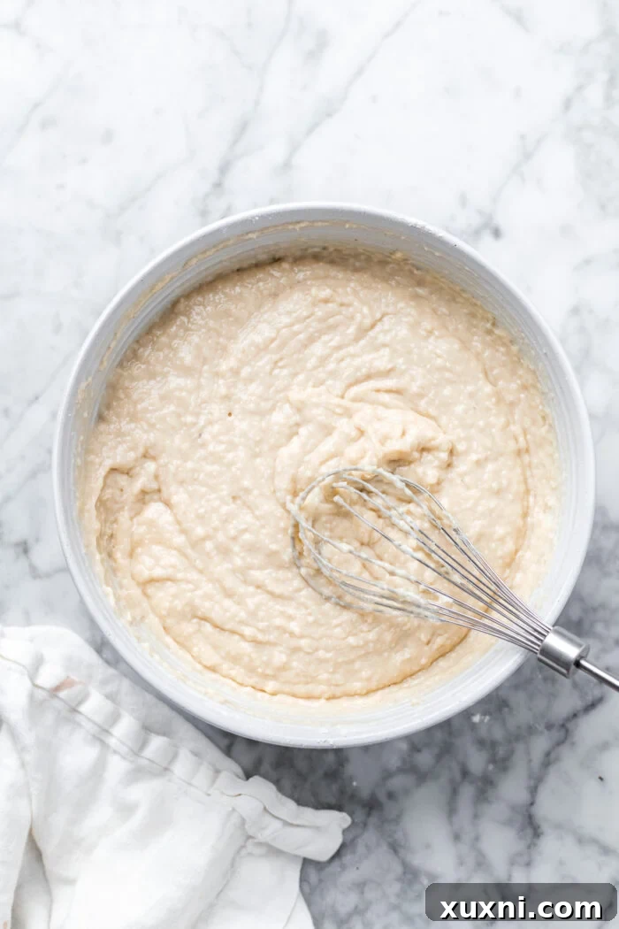 Vegan coconut cake batter poured into a prepared round cake pan, ready for baking.