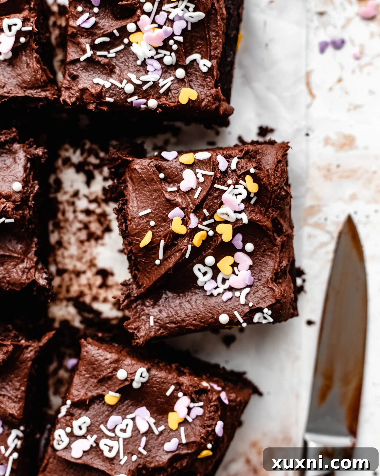 A perfectly sliced piece of vegan chocolate sheet cake for Valentine's Day, topped with sprinkles and ready to enjoy.