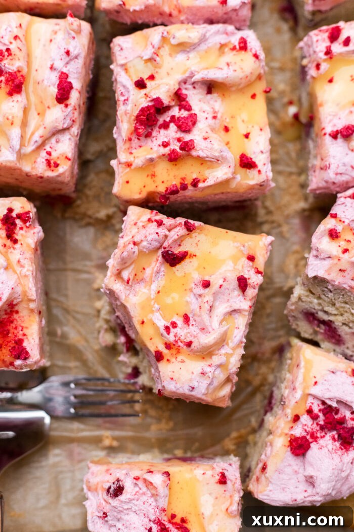 Zesty & Moist One-Bowl Vegan Raspberry Lemon Sheet Cake with Tangy Lemon Curd 4 A close-up of a frosted and sliced raspberry lemon cake, revealing layers of cake, frosting, and lemon curd.