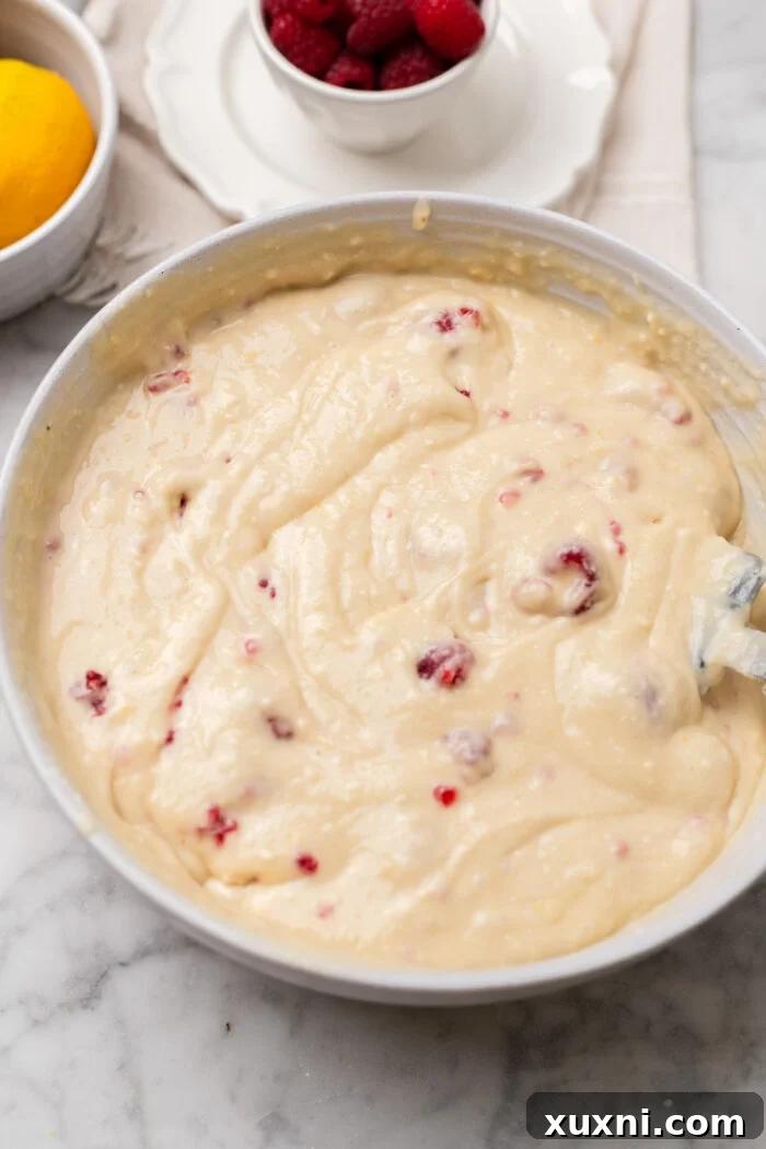 Zesty & Moist One-Bowl Vegan Raspberry Lemon Sheet Cake with Tangy Lemon Curd 6 The vibrant pink raspberry buttercream frosting spread on a delicate vegan lemon cake, ready to be decorated.