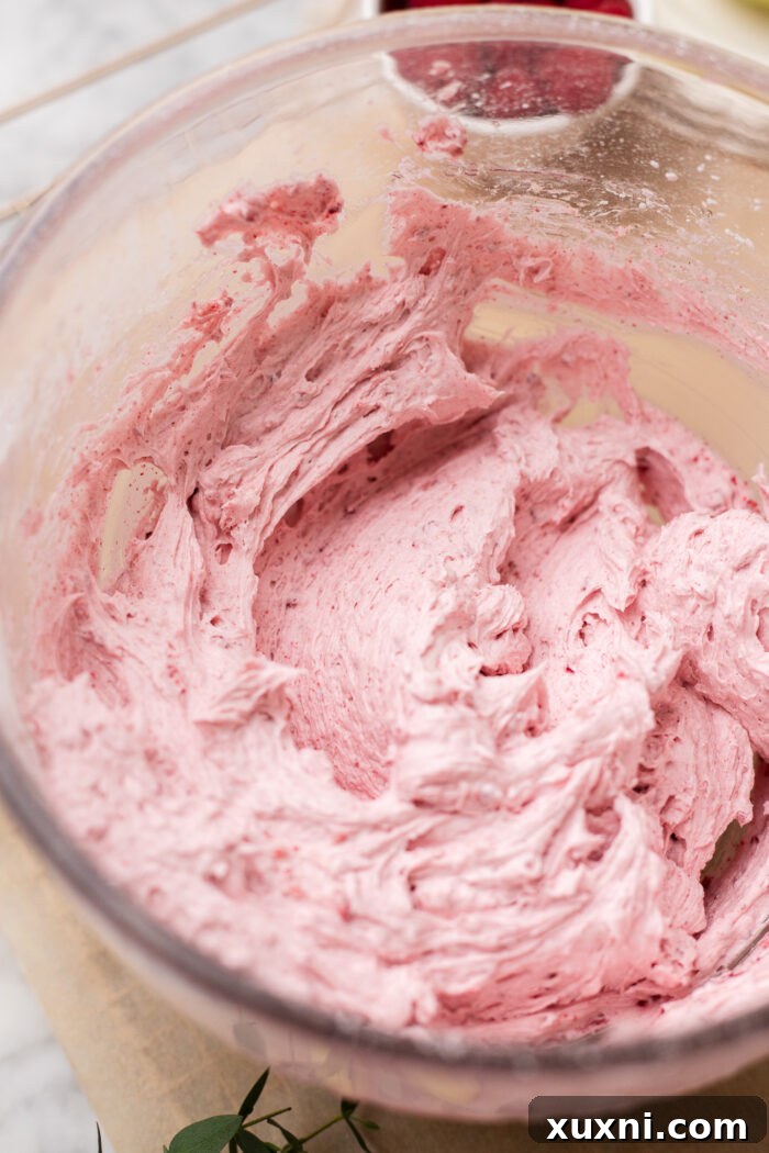 Zesty & Moist One-Bowl Vegan Raspberry Lemon Sheet Cake with Tangy Lemon Curd 7 Close-up of fluffy, pink raspberry frosting in a bowl, ready to be spread.
