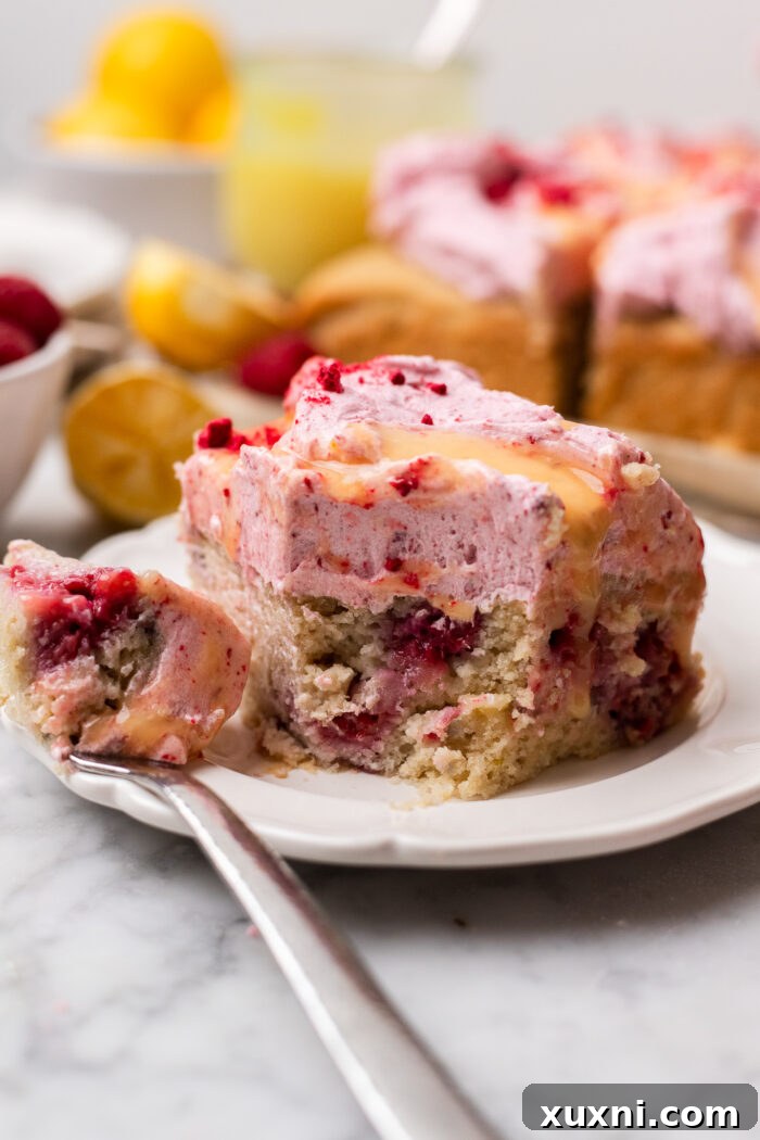 Zesty & Moist One-Bowl Vegan Raspberry Lemon Sheet Cake with Tangy Lemon Curd 9 A bitten slice of vegan raspberry lemon cake on a white plate, highlighting the delightful combination of flavors and textures.