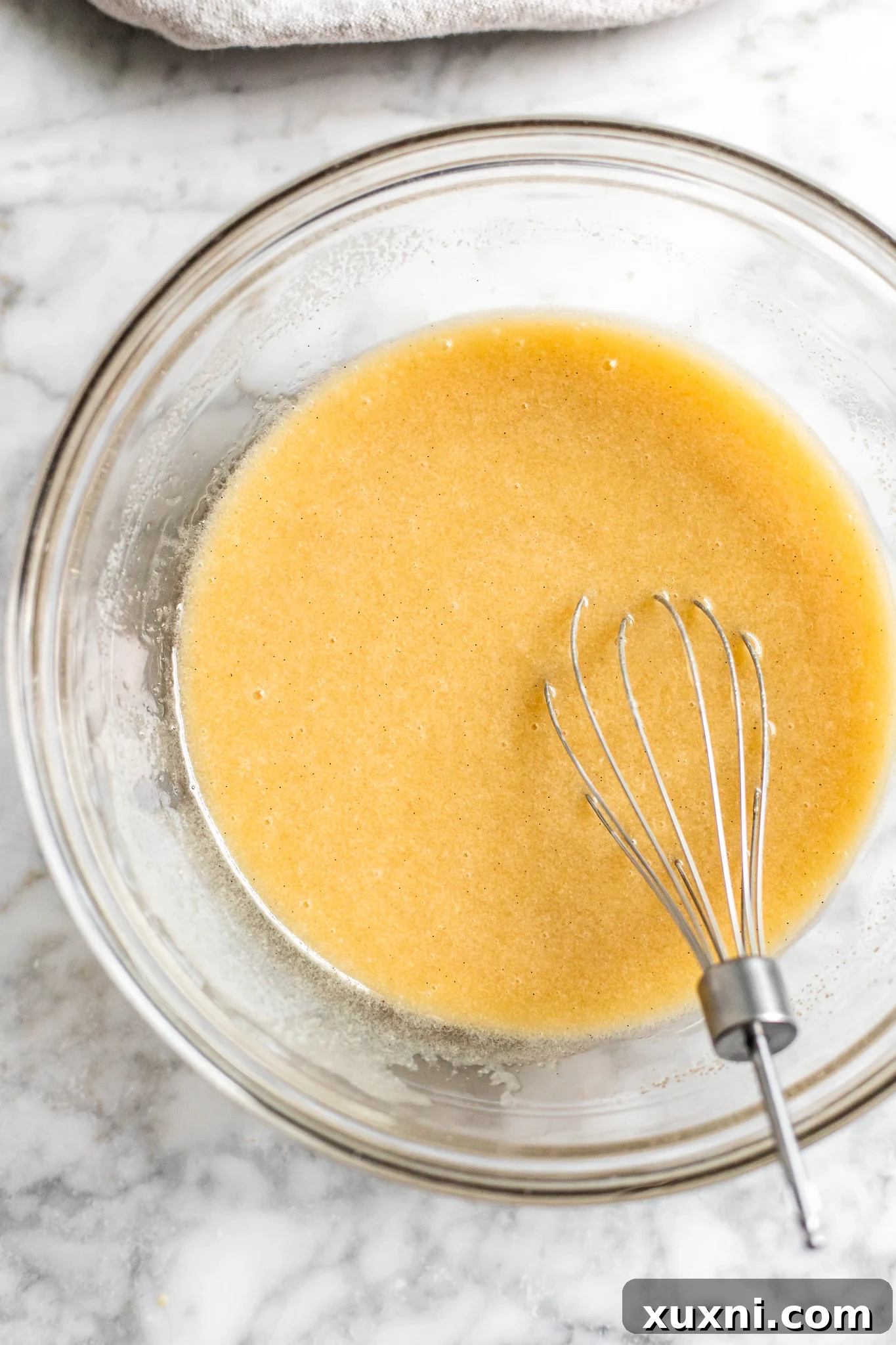 A bowl containing the wet ingredients for vegan chocolate chip muffins: vegan butter, oil, sugar, yogurt, and vanilla extract.