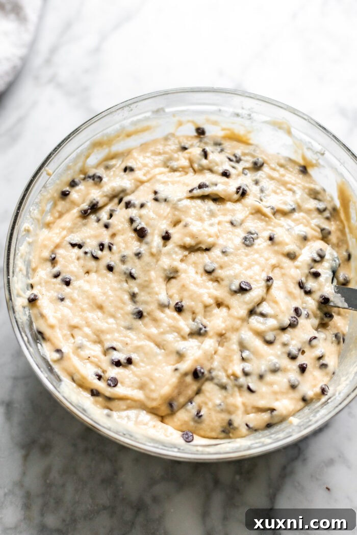 Close-up of fluffy vegan chocolate chip muffin batter in a bowl, with chocolate chips folded in.