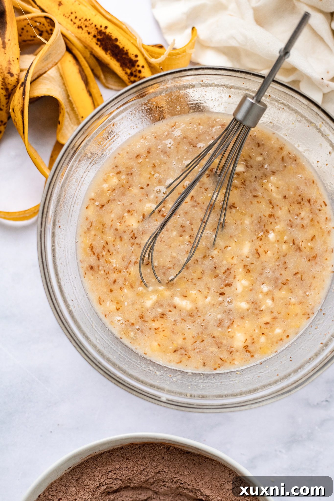 A bowl filled with the wet ingredients for vegan chocolate banana bread, including mashed bananas, sugar, and melted butter, ready for mixing.