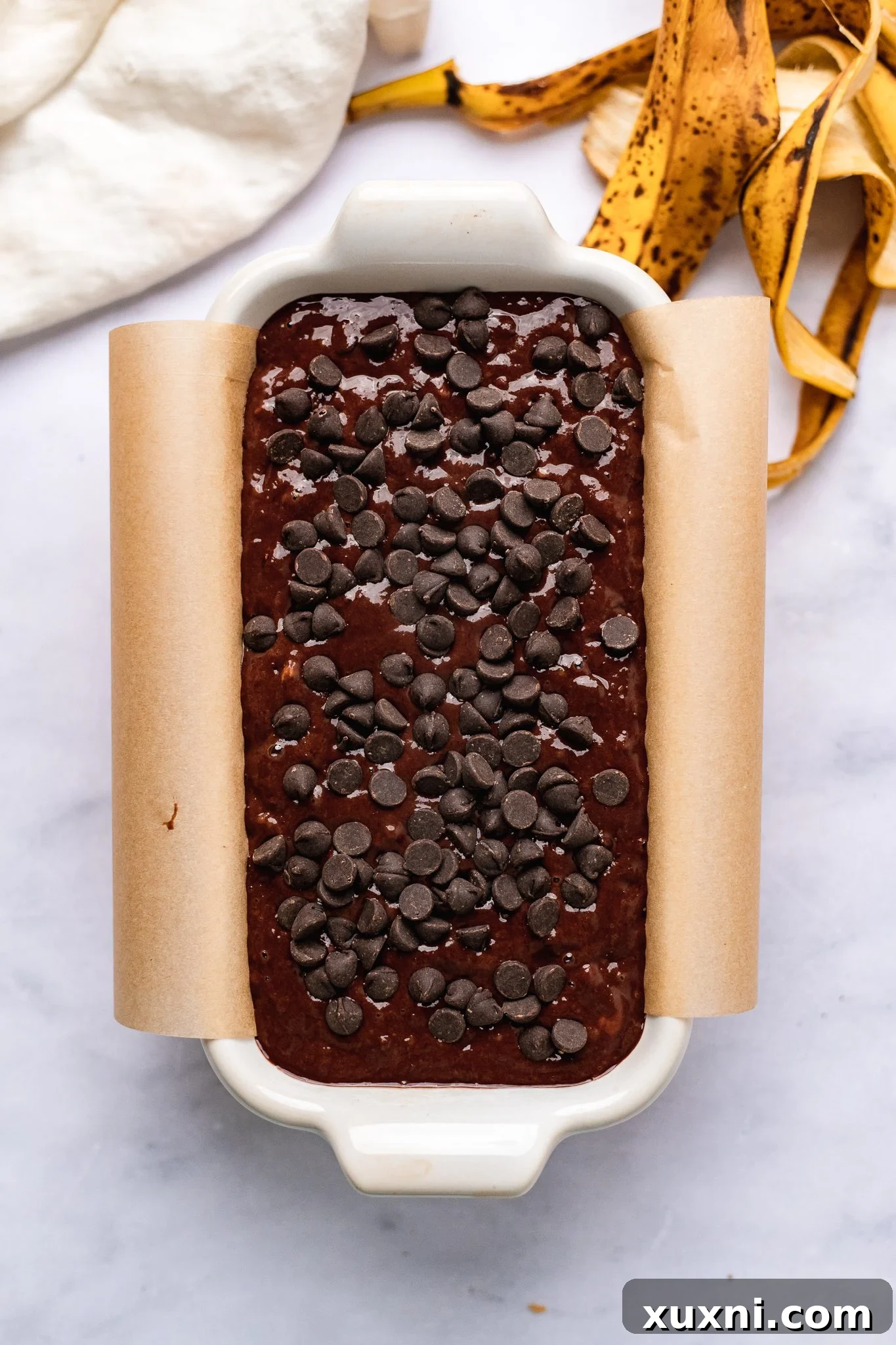 The unbaked vegan chocolate banana bread batter neatly poured into a loaf pan, topped with extra chocolate chips, awaiting its transformation in the oven.