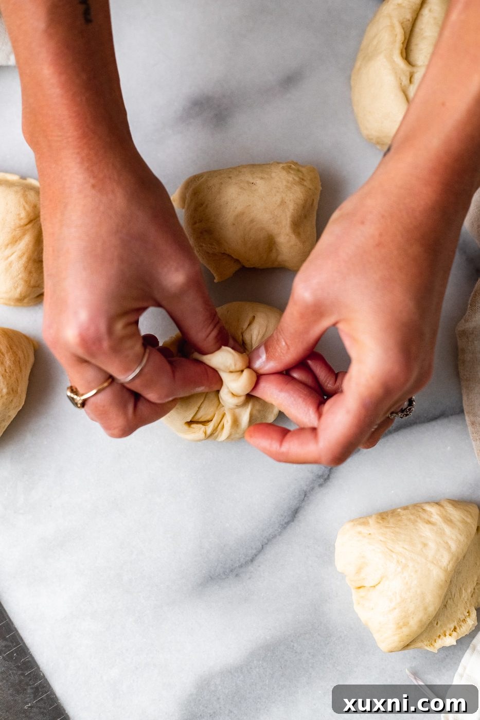 pinching the bottom of vegan dinner roll dough for smooth top