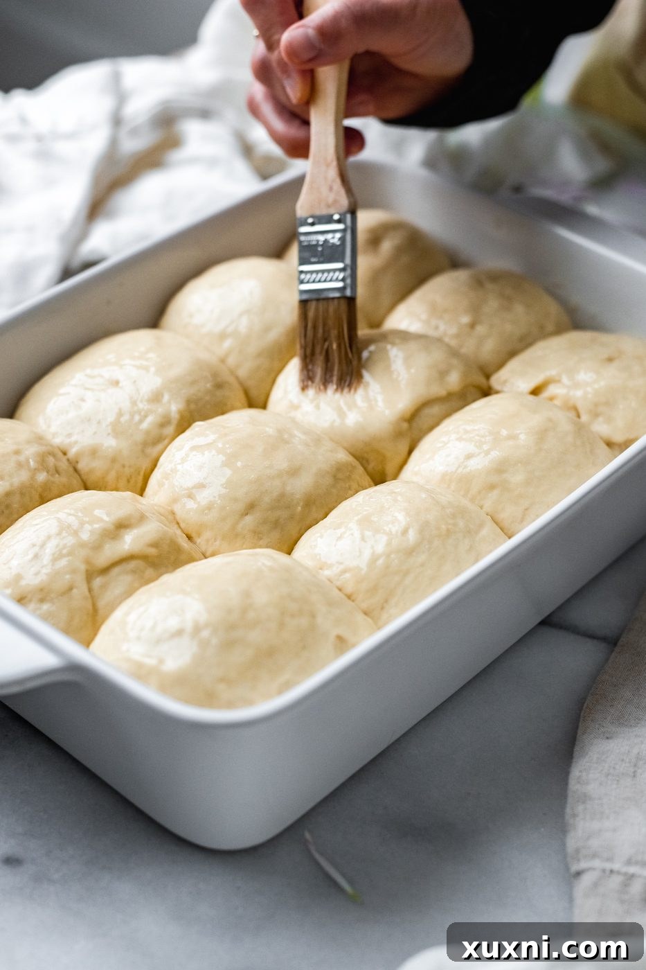 brushing vegan egg wash onto vegan dinner rolls before baking