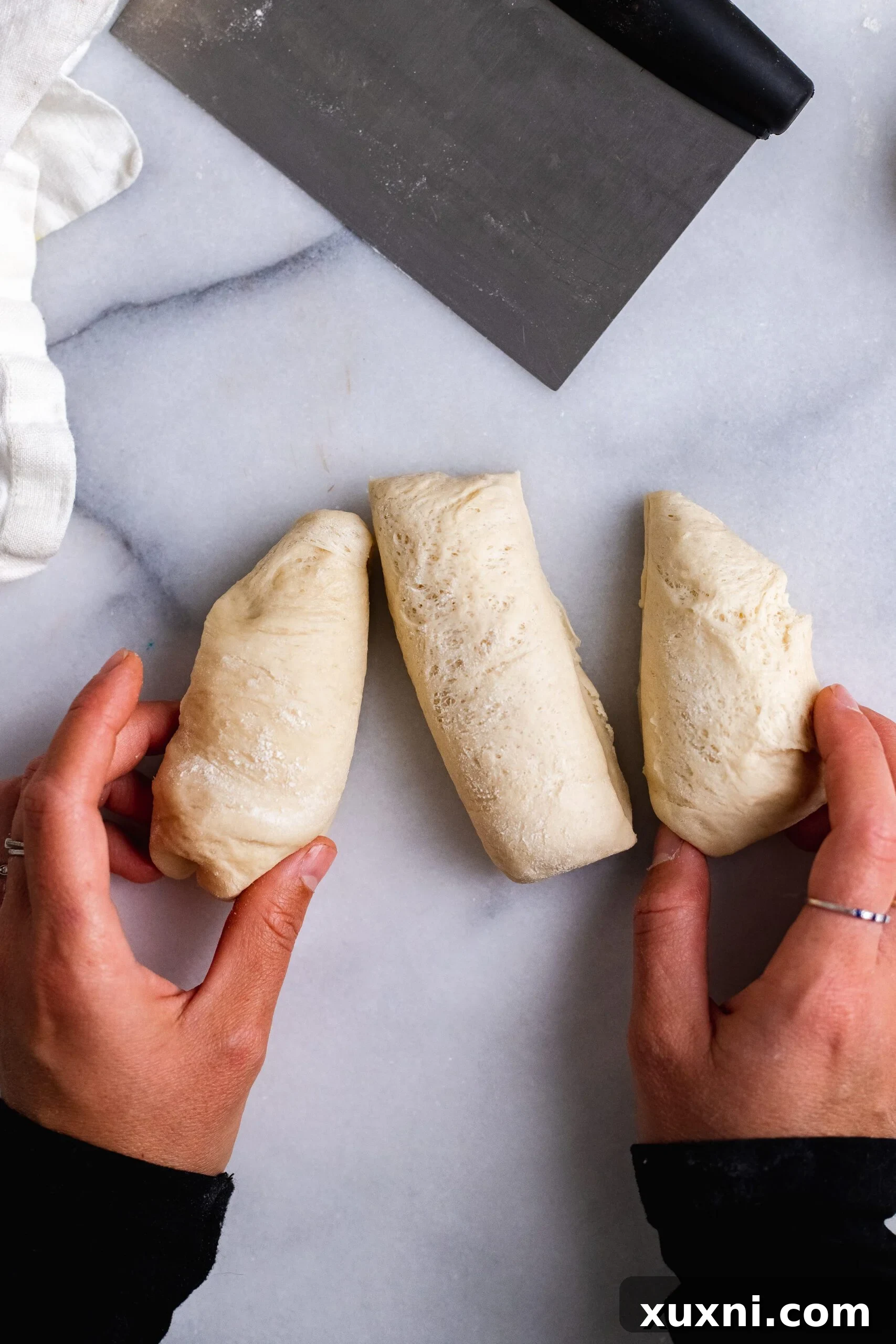 One piece of vegan Easter bread dough further divided into three smaller segments, ready for braiding.