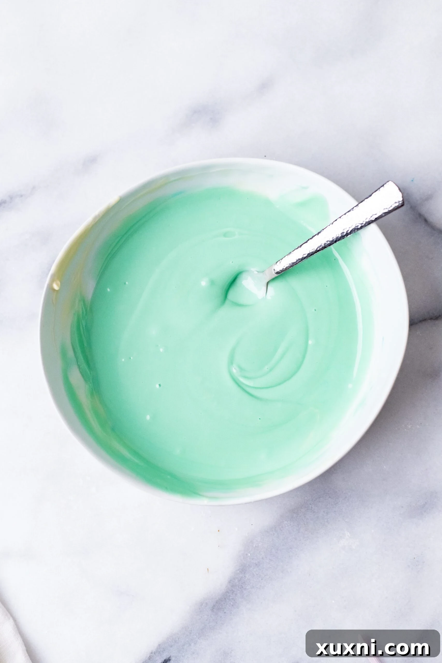 Melted vegan white chocolate infused with blue food coloring, perfectly mixed and ready for molding.