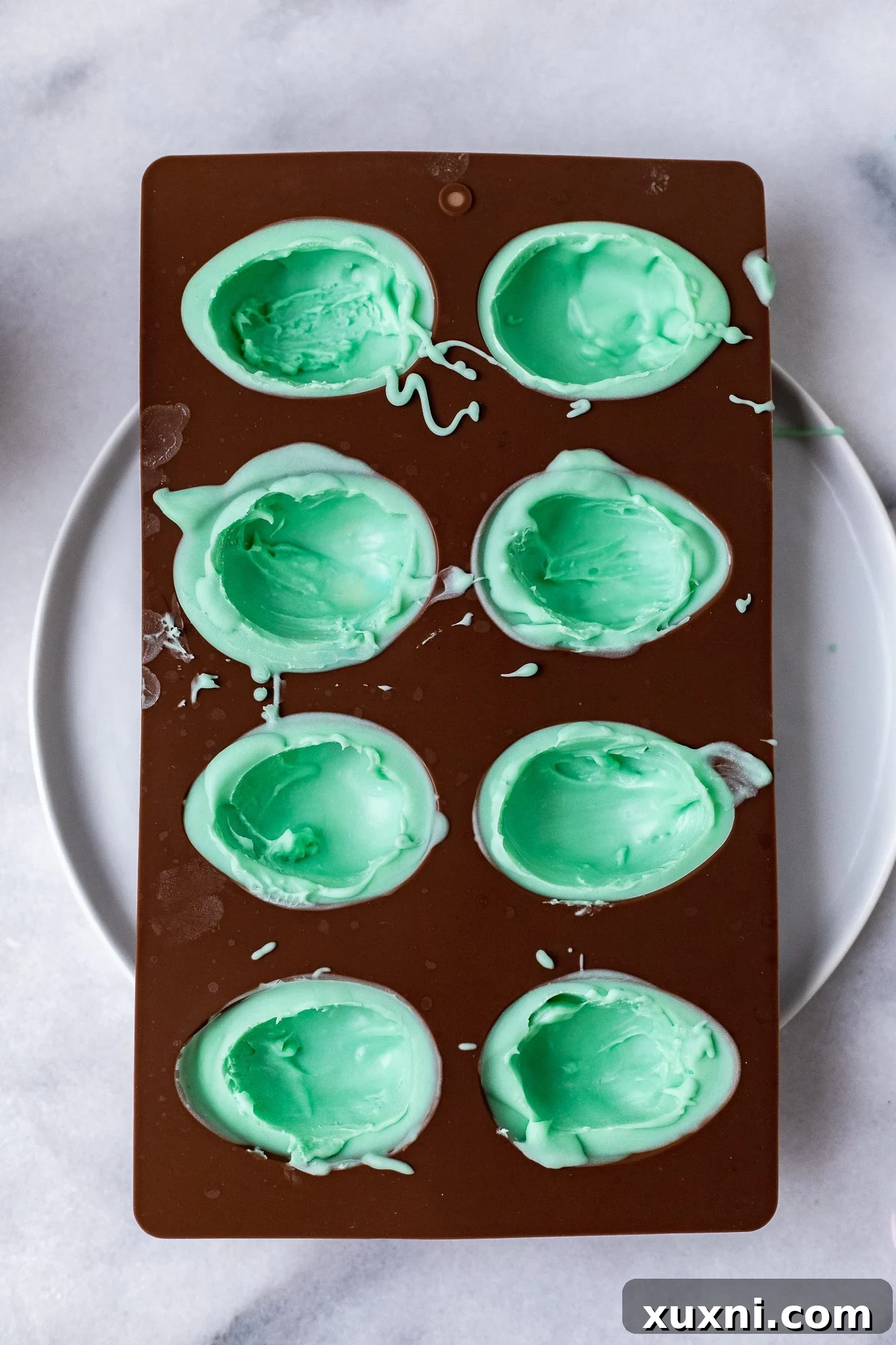 Scooped-out interiors of vegan white chocolate egg halves, creating cavities for sprinkles.