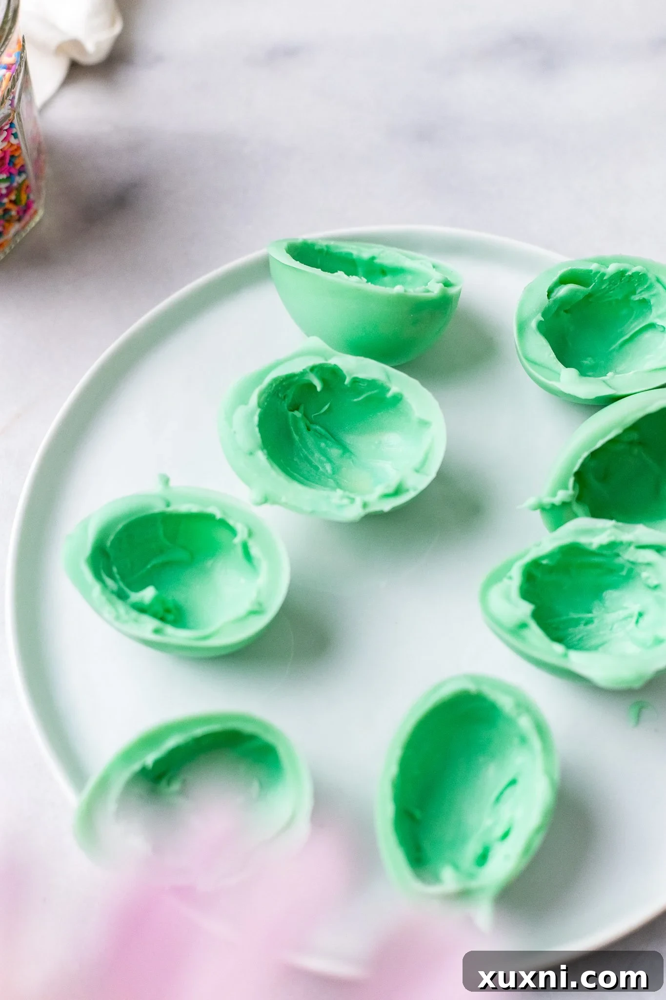 A collection of perfectly formed vegan white chocolate egg halves, ready for filling and sealing.