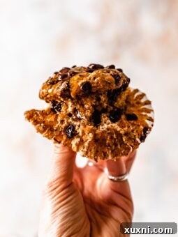A hand gently holding a single, perfectly baked vegan zucchini muffin, ready to be enjoyed.