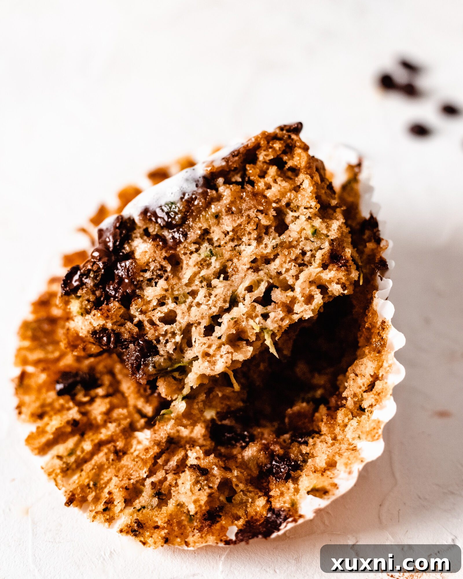 A close-up shot of perfectly sliced vegan zucchini muffins, revealing their tender crumb and chocolate chips.