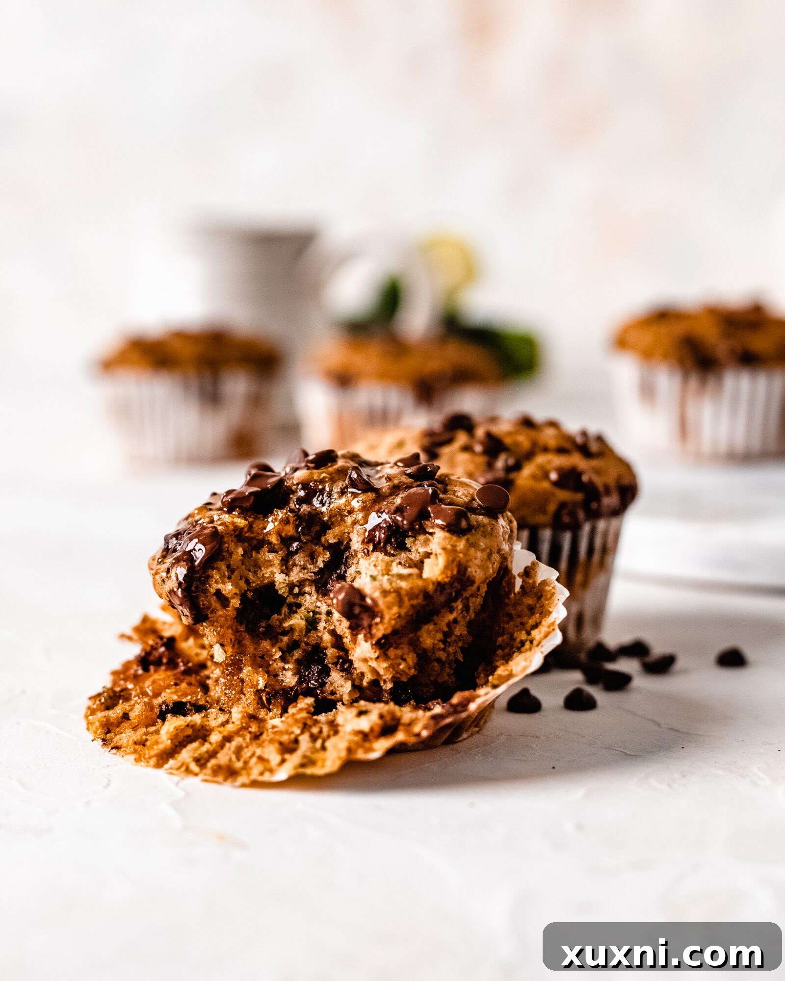 A delicious healthy vegan zucchini muffin with a bite taken out, revealing its soft and fluffy texture.