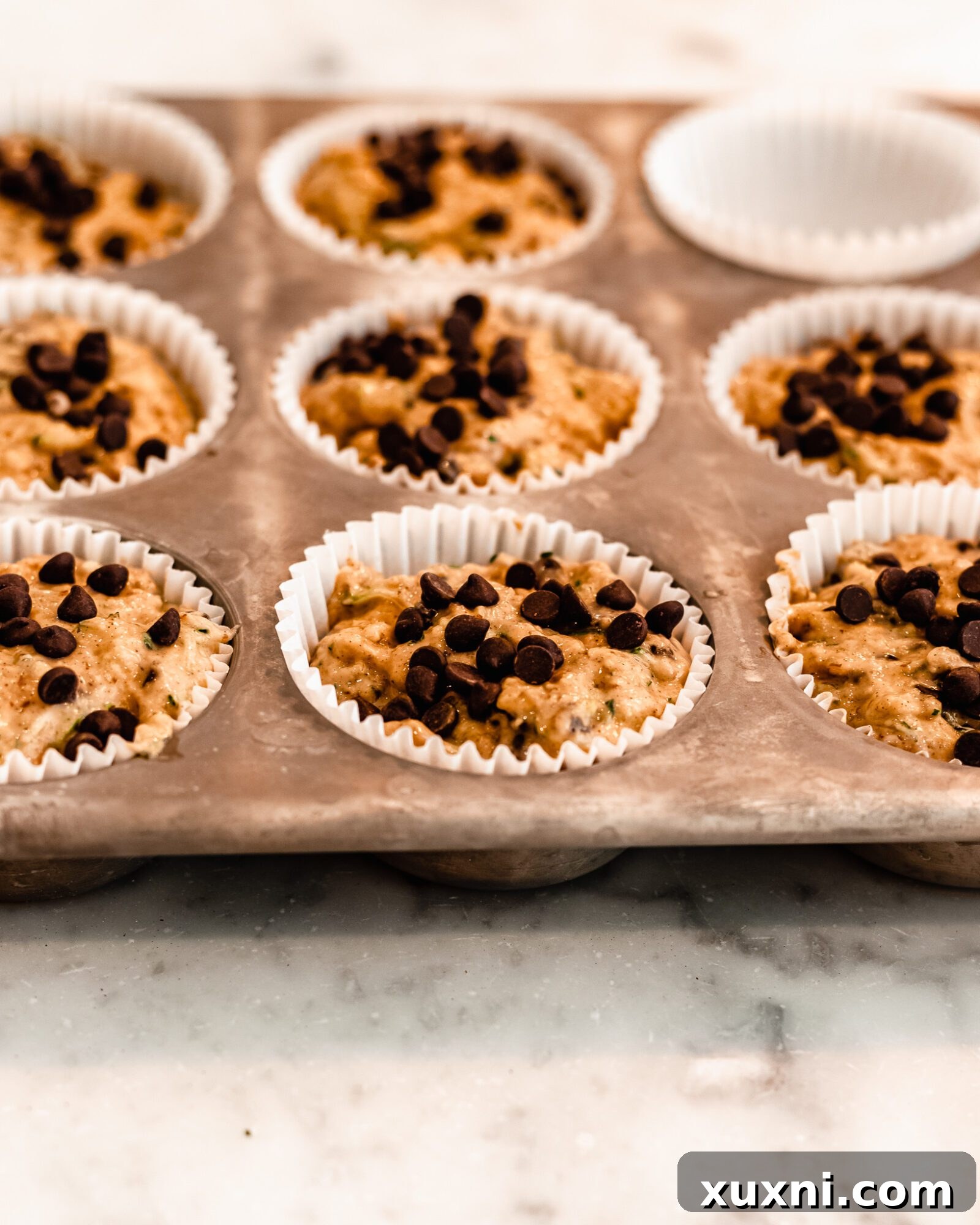 Vegan zucchini muffins neatly arranged in a muffin tin, ready for the oven.