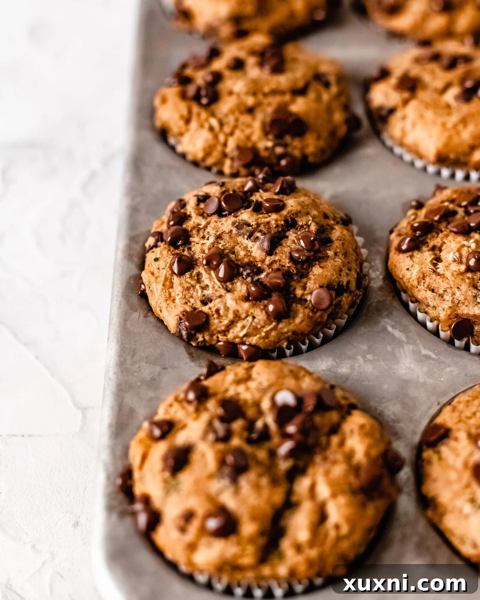 A fresh batch of golden-brown vegan zucchini muffins just pulled from the oven.