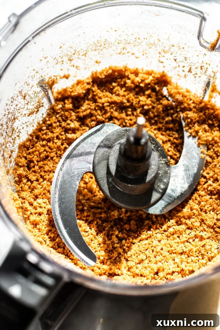 Graham cracker crust ingredients being processed in a food processor until fine crumbs are formed.